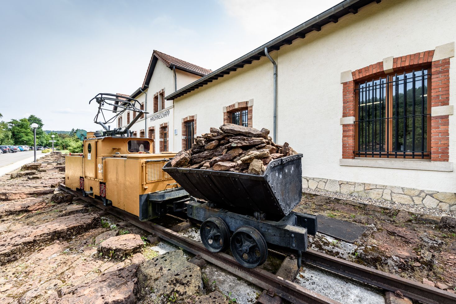 Ein Zugwagen und eine Lore sind vor dem Museum ausgestellt.