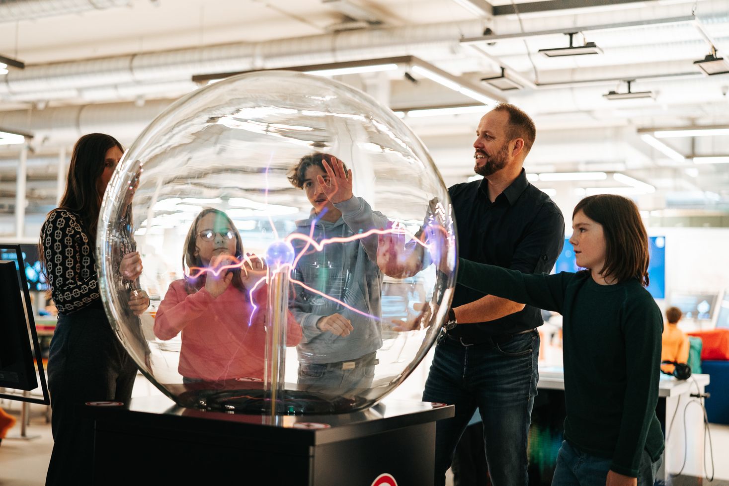Eine Familie an einer der Experimentstationen im Science Center, bei der es um Elektrizität geht