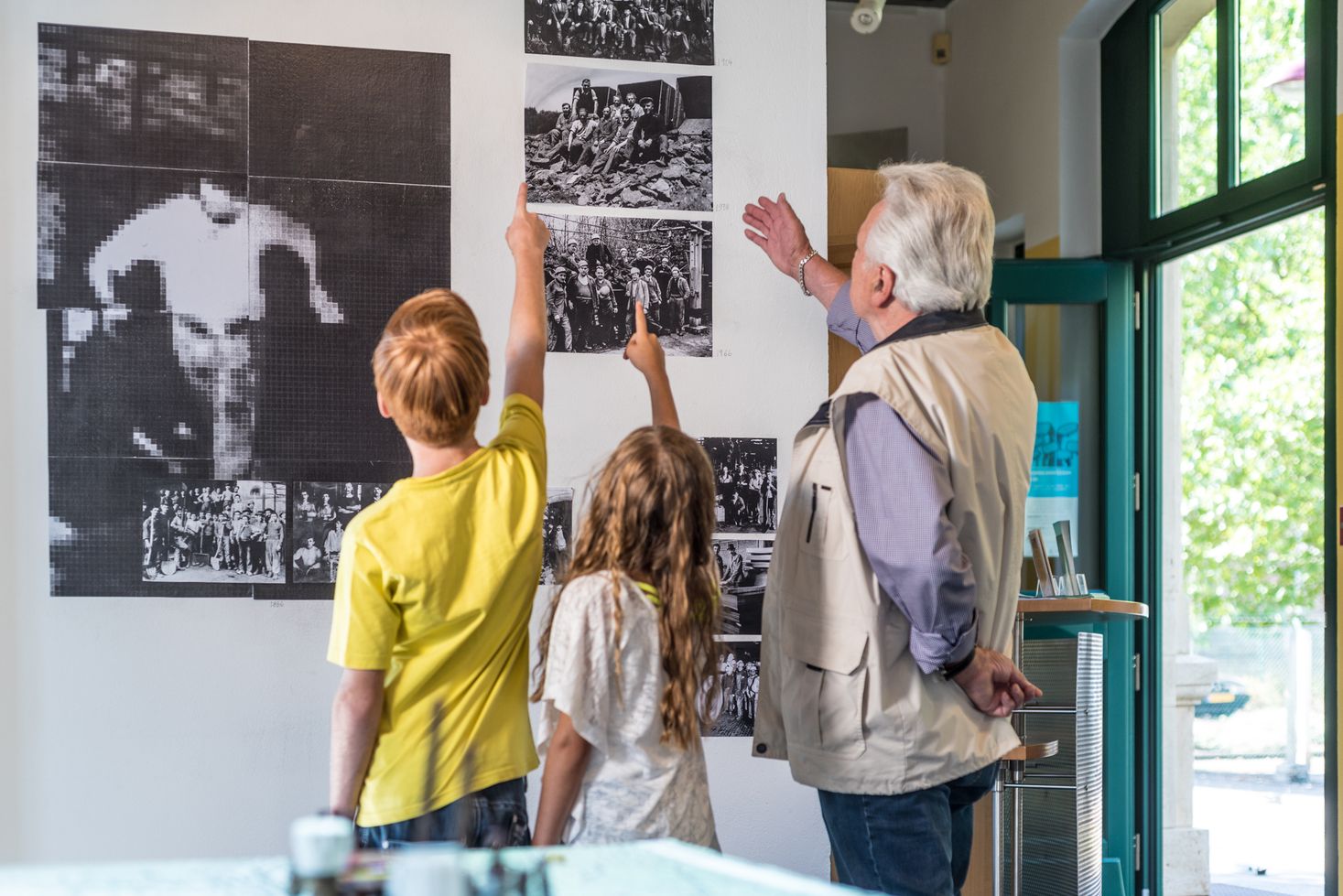 Une famille (deux enfants et un homme âgé) regardant la collection de photos du CDMH