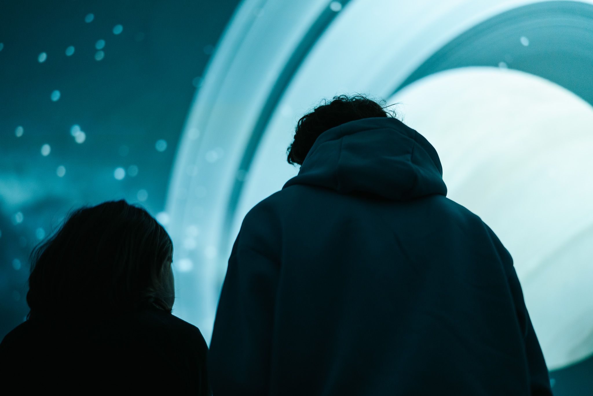 Die Silhouetten von zwei Besuchern vor dem Hintergrund des Planetariums im Science Center